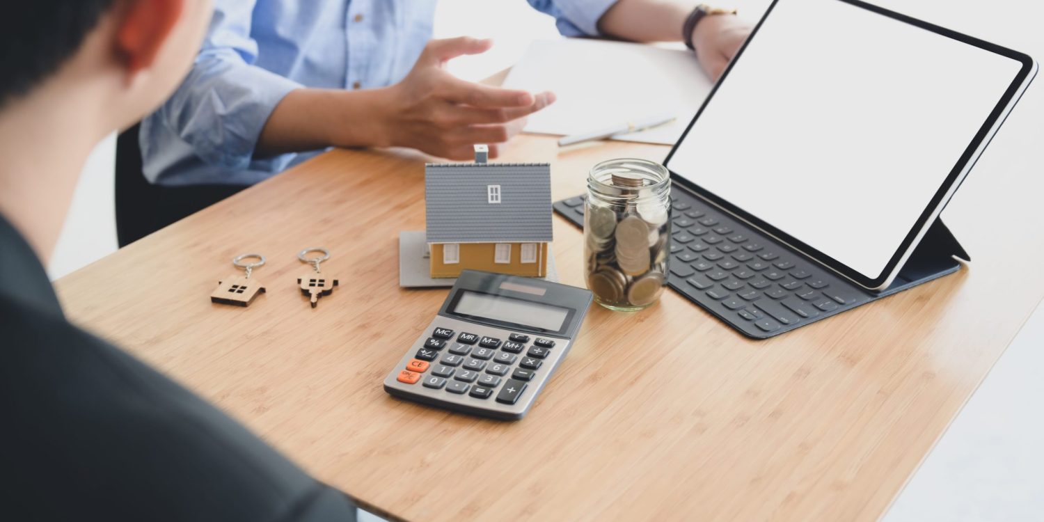 people calculating interest, taxes and profits to invest in real estate and home buying with mock up tablet and calculator